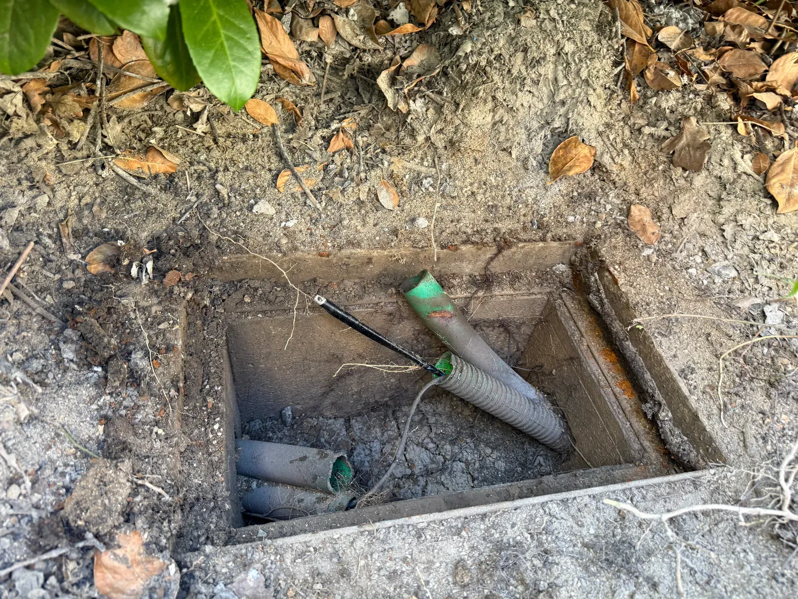 Chambre télécom ouverte à Mougins, avec les fourreaux accessibles après sa localisation dans le jardin