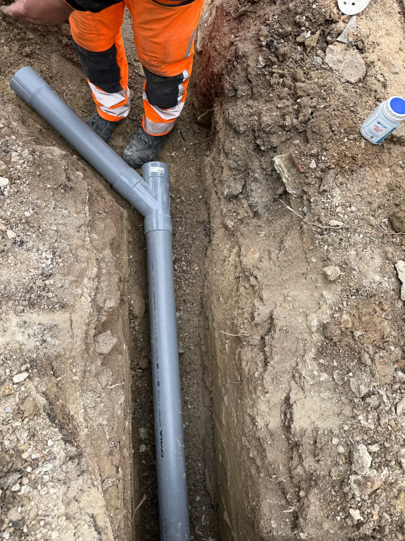 Pose et collage d'une canalisation PVC pour les eaux usées dans une tranchée