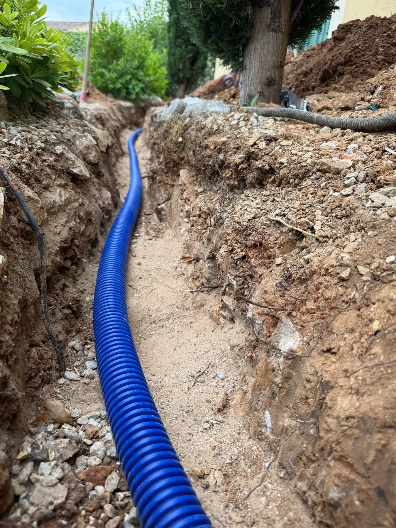 Nouvelle canalisation d'eau protégée par un fourreau bleu dans une tranchée à Biot
